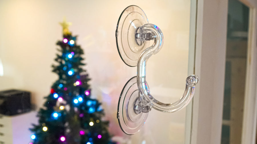 Suction cup sticking to a window next to a lit Christmas tree